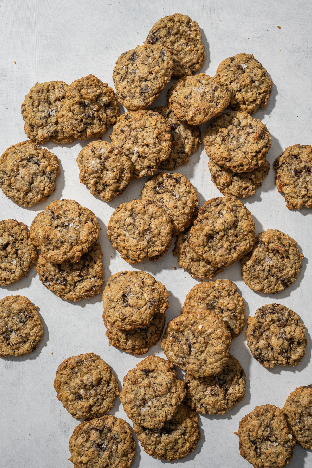 oatmeal chocolate chunk cookies with flake salt scattered around a table