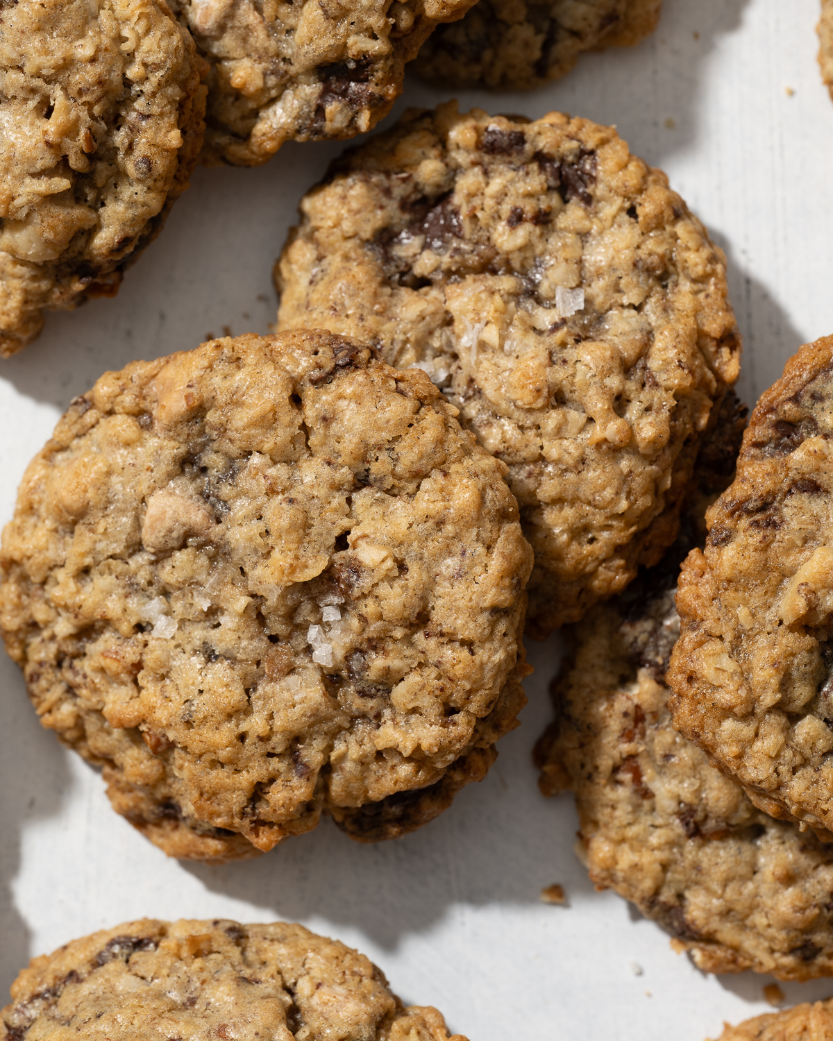 oatmeal chocolate chunk cookies with flake salt scattered around a table